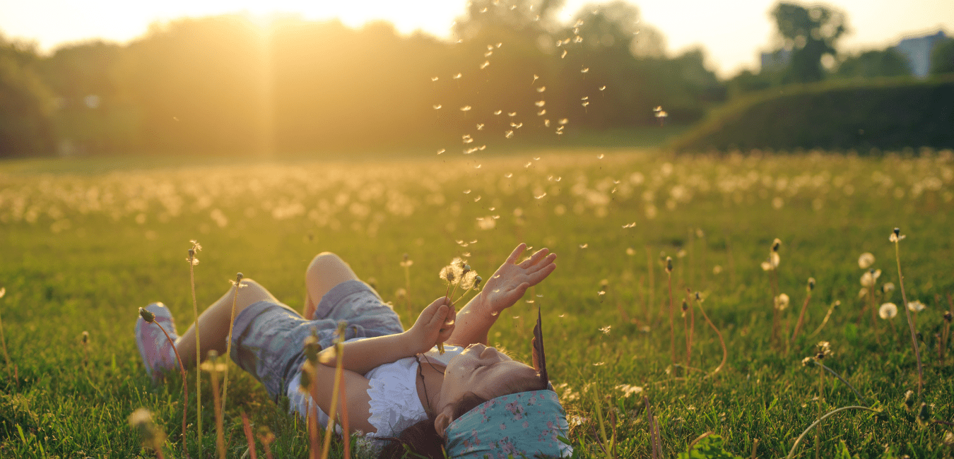 blog student stories summer bucket list. child laying in a meadow enjoying summer.