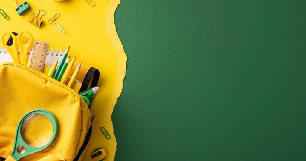 various school supplies scattered over yellow construction paper.