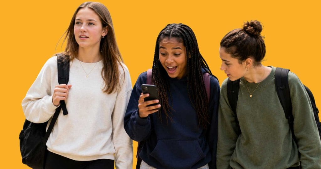 Three school kids walking with backpacks and one looking at a phone
